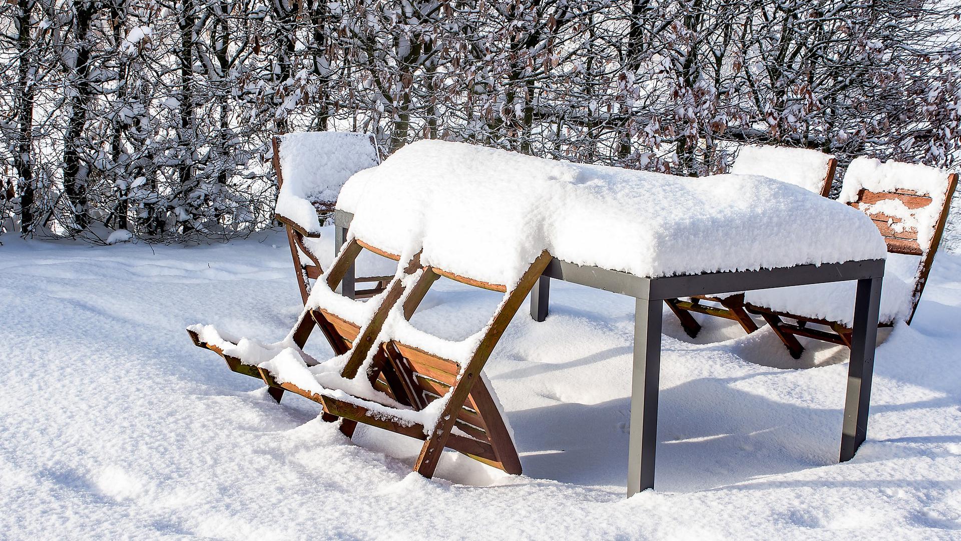 Schneebedeckte Gartenmöbel im Winter